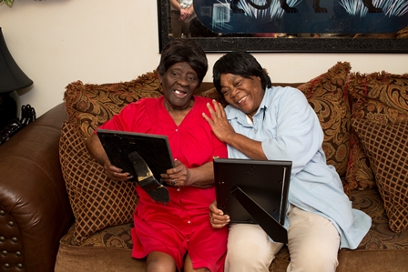 Two women sitting on couch looking at framed photos